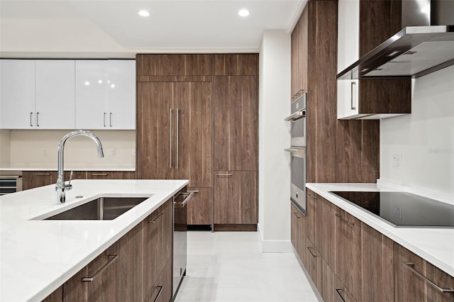 kitchen featuring sink, light stone counters, stainless steel appliances, wall chimney exhaust hood, and white cabinets