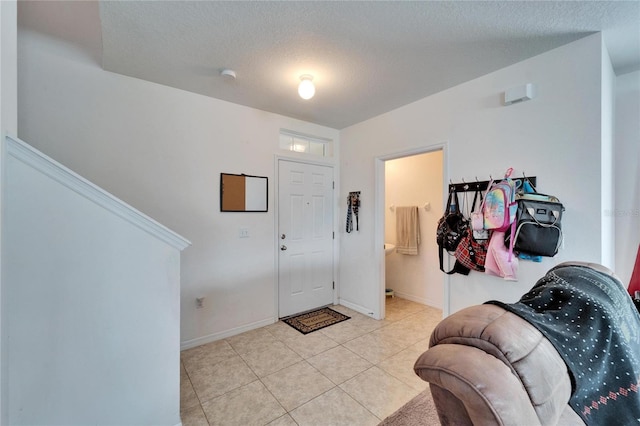 foyer entrance with light tile patterned floors, baseboards, and a textured ceiling