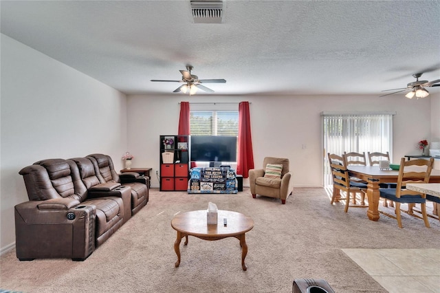 carpeted living room with a textured ceiling, visible vents, and a ceiling fan