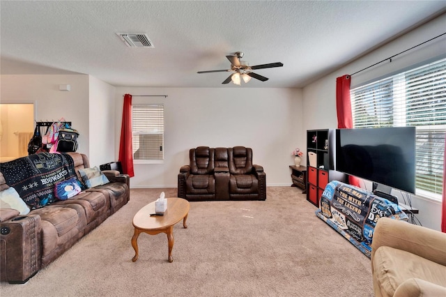 living area with light colored carpet, visible vents, ceiling fan, and a textured ceiling