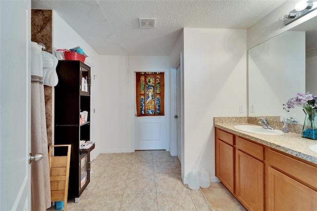 full bathroom featuring double vanity, visible vents, tile patterned flooring, a textured ceiling, and a sink