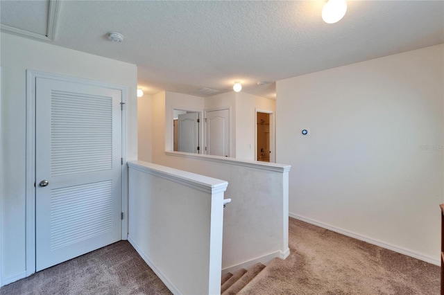 kitchen featuring a textured ceiling, a peninsula, carpet, and baseboards