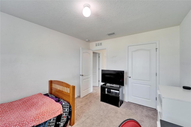 bedroom with visible vents, a textured ceiling, and light colored carpet