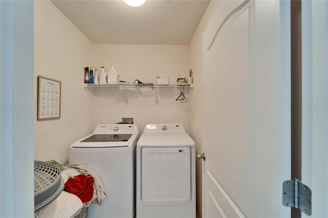 washroom with a textured ceiling, laundry area, and washing machine and dryer