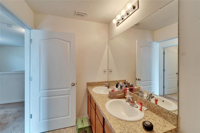 full bathroom featuring double vanity, a textured ceiling, and a sink