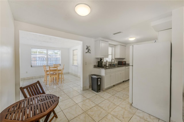 kitchen featuring sink, light tile patterned flooring, white cabinets, and white fridge