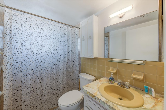 bathroom with walk in shower, tile walls, vanity, and toilet