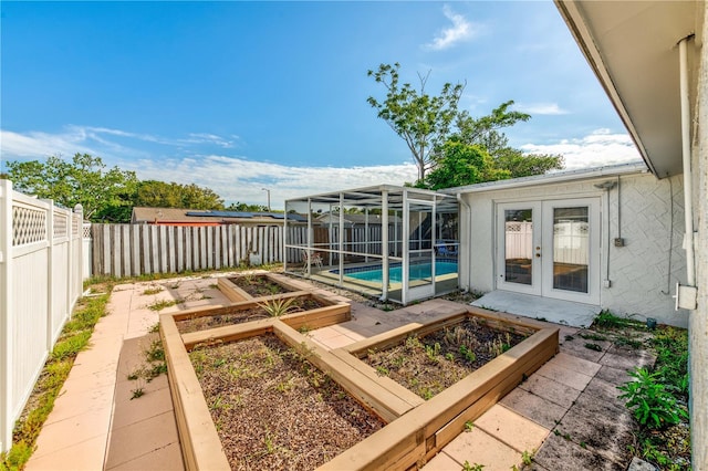 view of yard featuring french doors, a patio, a fenced in pool, and glass enclosure