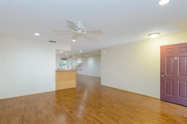 empty room featuring a textured ceiling, light hardwood / wood-style floors, and ceiling fan