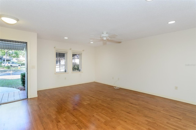 empty room featuring ceiling fan, a wealth of natural light, and wood-type flooring