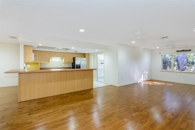 interior space with ceiling fan, stainless steel fridge, light brown cabinetry, and light hardwood / wood-style floors