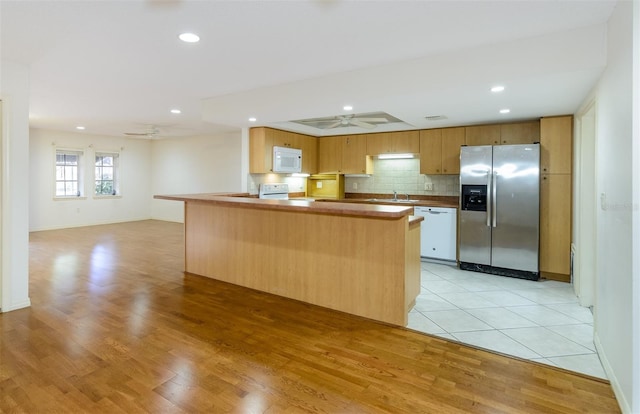 kitchen featuring tasteful backsplash, ceiling fan, white appliances, and kitchen peninsula