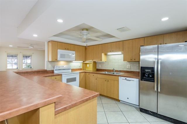 kitchen with sink, white appliances, ceiling fan, a tray ceiling, and kitchen peninsula