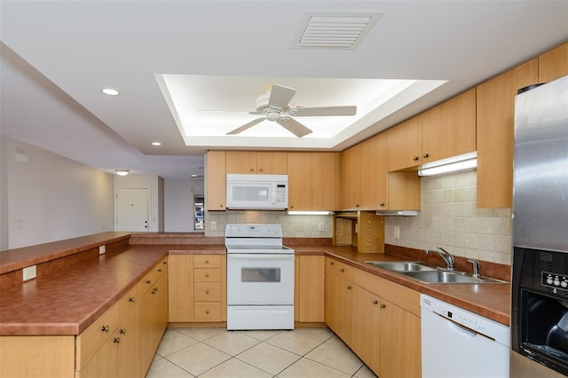 kitchen featuring sink, white appliances, a tray ceiling, light tile patterned flooring, and decorative backsplash