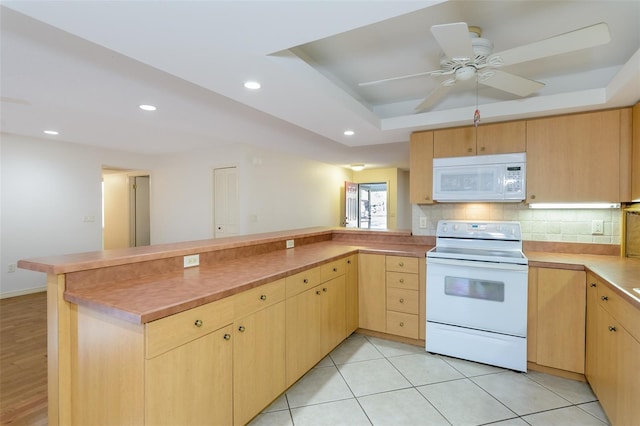 kitchen with light brown cabinetry, a tray ceiling, kitchen peninsula, white appliances, and backsplash