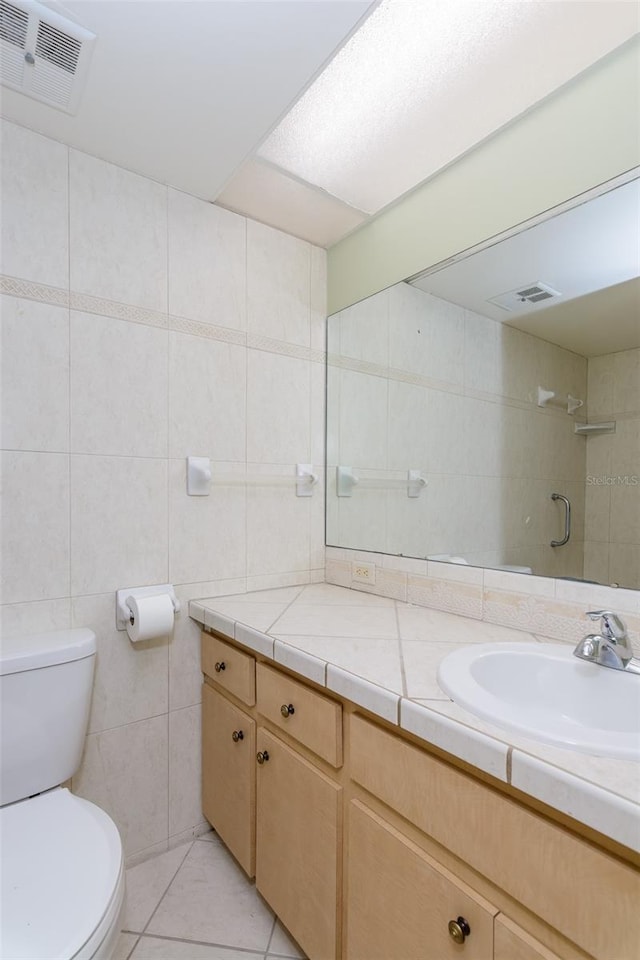 bathroom featuring tile patterned floors, vanity, toilet, and tile walls