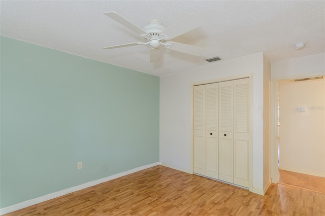 unfurnished bedroom featuring ceiling fan, a textured ceiling, light wood-type flooring, and a closet