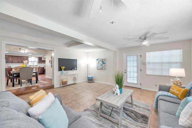 living room with light tile patterned flooring, ceiling fan, and a textured ceiling