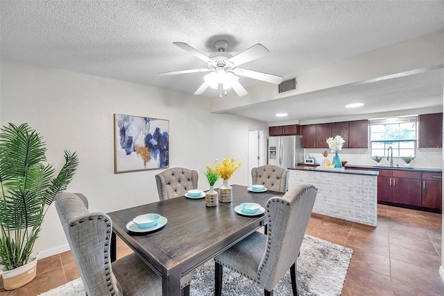 tiled dining area featuring sink, a textured ceiling, and ceiling fan