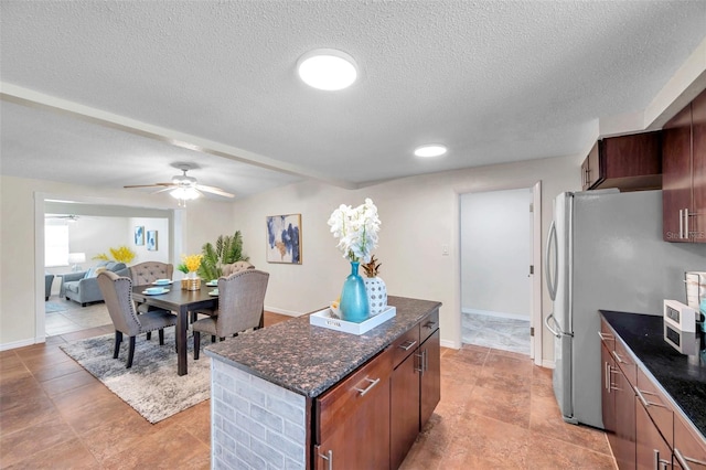 kitchen with a textured ceiling, stainless steel refrigerator, ceiling fan, and a center island