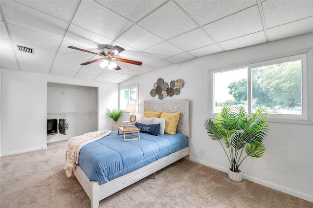 bedroom with carpet floors, ceiling fan, and a paneled ceiling