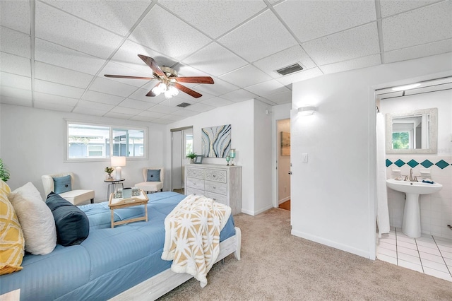 bedroom with light colored carpet, a drop ceiling, ceiling fan, and tile walls