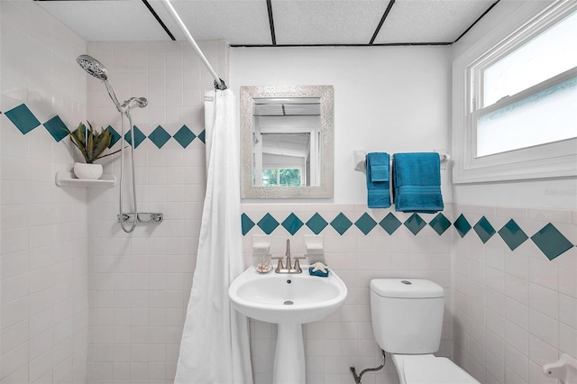 bathroom with plenty of natural light, curtained shower, tile walls, and toilet