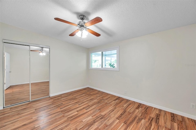 unfurnished bedroom with ceiling fan, light hardwood / wood-style flooring, a closet, and a textured ceiling