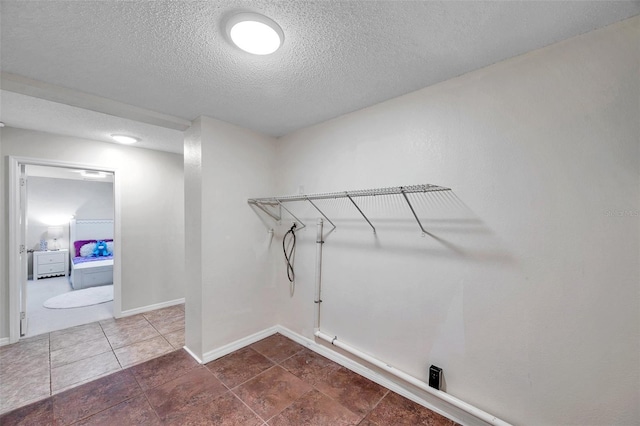 laundry area with dark tile patterned flooring and a textured ceiling