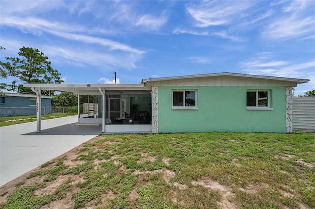 back of house with a carport, a sunroom, and a lawn