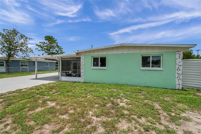 back of house with a carport, a sunroom, and a lawn