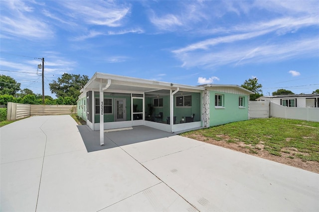 rear view of house featuring a patio area, a sunroom, and a lawn