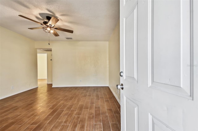 unfurnished room with ceiling fan, a textured ceiling, and dark hardwood / wood-style flooring