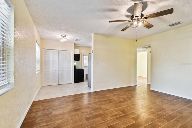 empty room with wood-type flooring, ceiling fan, and a textured ceiling