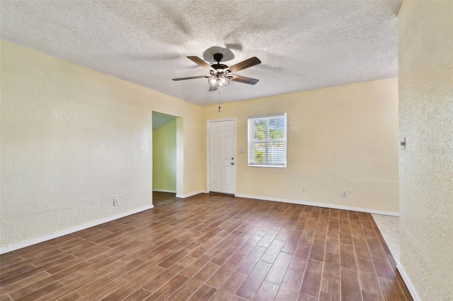 empty room featuring a textured ceiling, dark hardwood / wood-style floors, and ceiling fan