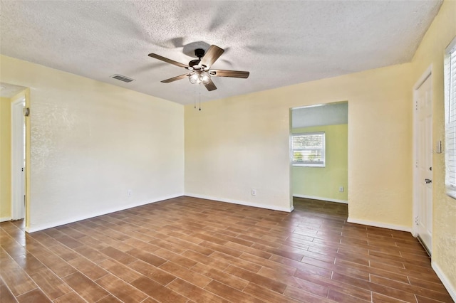 empty room featuring dark wood-type flooring, a textured ceiling, and ceiling fan