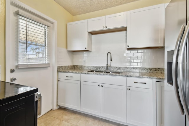 kitchen featuring sink, white cabinetry, stainless steel fridge with ice dispenser, light stone countertops, and backsplash