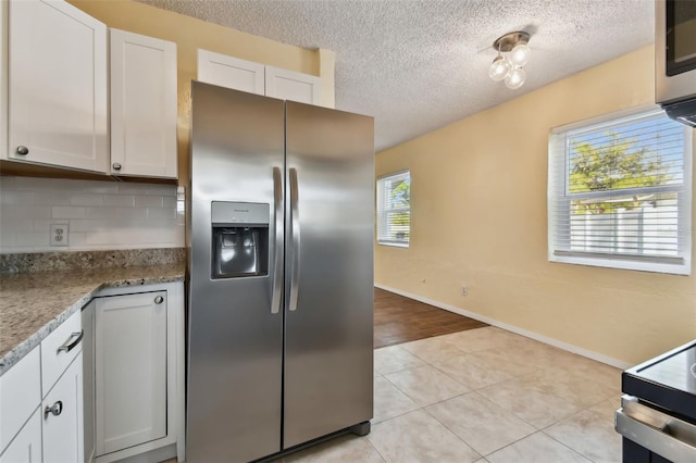 kitchen featuring white cabinetry, appliances with stainless steel finishes, light stone countertops, and decorative backsplash