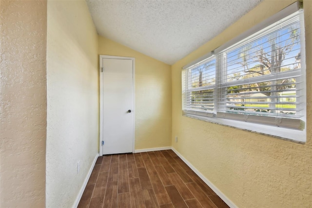 corridor featuring lofted ceiling and a textured ceiling