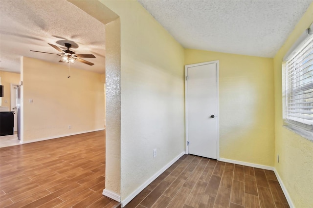 spare room featuring ceiling fan, vaulted ceiling, and a textured ceiling