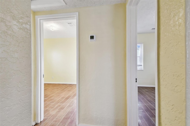 hall with hardwood / wood-style flooring and a textured ceiling