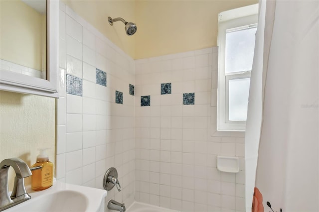 bathroom with tiled shower / bath combo and sink