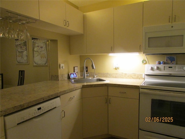 kitchen featuring white appliances, kitchen peninsula, and sink