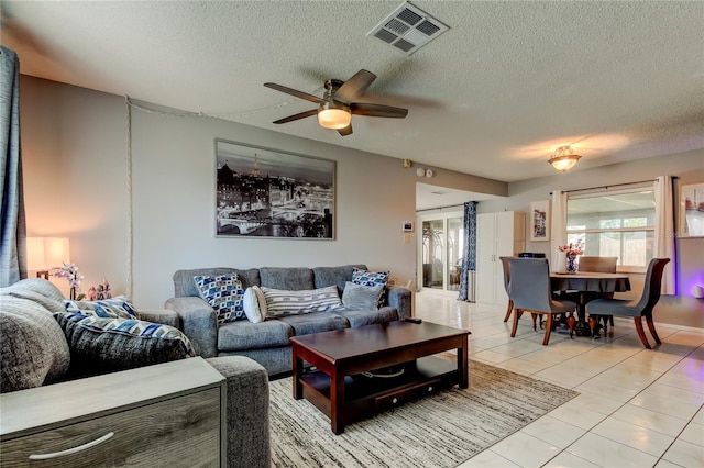 tiled living room featuring ceiling fan and a textured ceiling