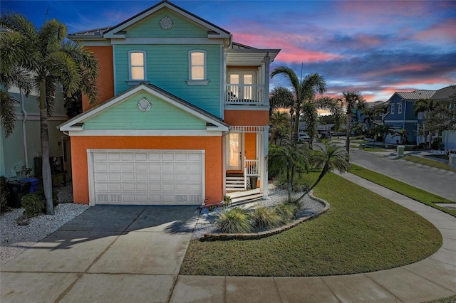 view of front property with a balcony, a garage, and a yard