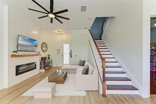 living room featuring crown molding, a fireplace, and light hardwood / wood-style floors