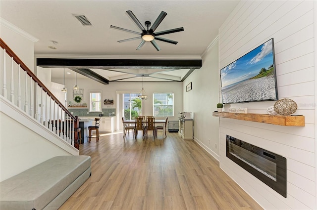 living room featuring ornamental molding, beam ceiling, and light wood-type flooring