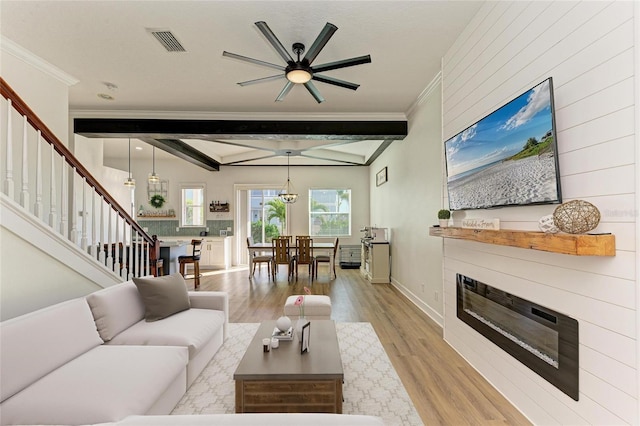 living room with beamed ceiling, ornamental molding, and light hardwood / wood-style floors