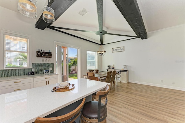 kitchen with decorative light fixtures, beamed ceiling, white cabinets, plenty of natural light, and light hardwood / wood-style flooring