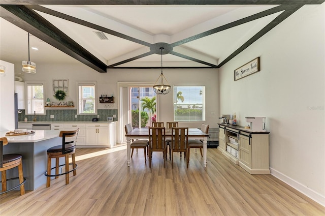 dining area featuring vaulted ceiling with beams, an inviting chandelier, and light wood-type flooring